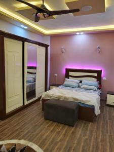 a bedroom with a large bed with purple lighting at Cosy appartment in city in Luxor