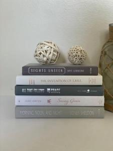 a stack of books on a shelf with two vases at Mamma House in Melrose