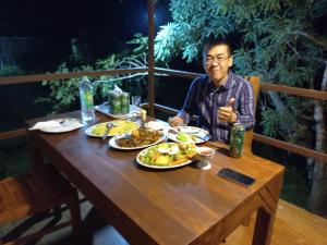 a man sitting at a table with plates of food at LLT budget room WILPATTU in Nochchiyagama