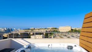 a bath tub on a balcony with a view of a city at Tritoni Valletta Boutique Hotel in Il-Furjana