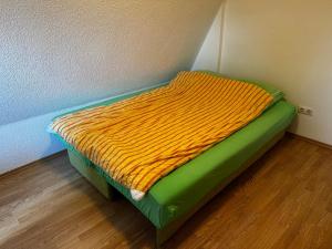 ein kleines Bett mit einer Orange- und Gründecke darauf in der Unterkunft VIKENDICA TOJA - Brcko in Brčko