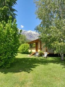 a house with two chairs in a yard at Cabañas Tierra Verde in El Bolsón