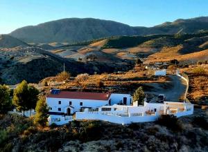 biały dom na wzgórzu z górami w tle w obiekcie Cortijo naturista con vistas-clothing optional w mieście Oria