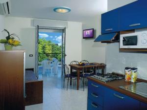 una cucina con armadi blu e vista su un tavolo di Residence Regent Beach a Bibione