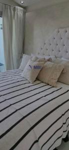 a bed with a white and black striped comforter and pillows at Tangier Mediterranean Villa in Tangier