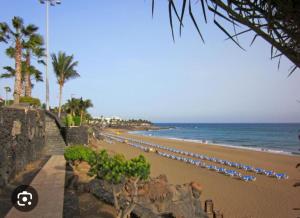 a beach with a bunch of umbrellas and the ocean at Puerto del Carmen Las caracolas Acogedor espacioso y luminoso apartamento cerca del mar in Puerto del Carmen +7 photos