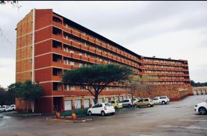 a large brick building with cars parked in a parking lot at Jirah@Riverside in Centurion