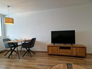 Apartment Pilz في غوساو: غرفة معيشة مع تلفزيون بشاشة مسطحة على مركز ترفيهي خشبي