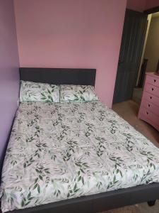 een bed in een roze kamer met een witte sprei bij Royal house in Ilkeston