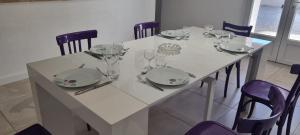 una mesa blanca con platos y copas de vino. en La maison de Mamé en Arles
