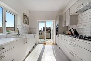 a kitchen with white cabinets and a large window at 3BD Retreat Boothstown Manchester in Ellenbrook