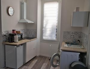 a kitchen with white cabinets and a window and a sink at Logement spacieux centre Joigny 4 à 6 pers - Zen 2 in Joigny +4 photos