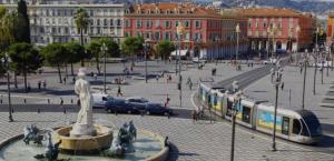 a train in a city with a street with people at Chambre privée confortable à louer chez l habitant proche plage et centre ville de Nice in Nice