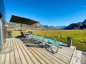 una terraza con sillas, una mesa y una sombrilla en Charmant logement entre Lac et Montagne en Rochebrune