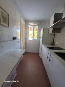 a white kitchen with a counter and a sink at Novo Sancti Petri - Playa, Piscina, Golf y Relax in Chiclana de la Frontera