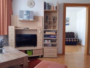 - un salon avec une télévision et une étagère dans l'établissement Ferienwohnung Eva, à Längenfeld