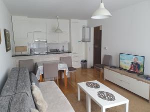 ein Wohnzimmer mit einem Sofa und Tischen sowie eine Küche in der Unterkunft Apartman Relax Bjelašnica in Trnovo