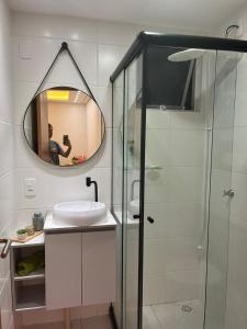 ein Badezimmer mit Waschbecken und Dusche mit Spiegel in der Unterkunft Apê pé na areia com vista mar e próximo ao Beto Carrero - Condomínio Vila Açoriana in Barra Velha