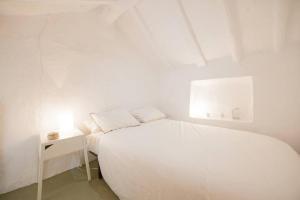 Dormitorio blanco con cama blanca y mesita de noche en Casita avec superbe vue et piscine privée en Algodonales