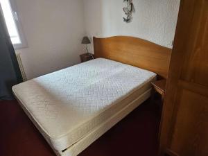 Dormitorio pequeño con cama con cabecero de madera en L'Atelier Obelix familiale de 1 à 4 personnes, en Saint-Symphorien-de-Marmagne