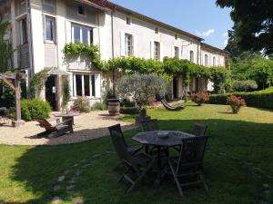 patio ze stołem i krzesłami przed budynkiem w obiekcie Au Ruisseau de Rose w mieście Saint-Jean-du-Gard