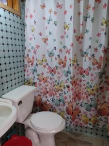 a bathroom with a toilet and a shower curtain with butterflies at Hospedaje Martita. in Putemún