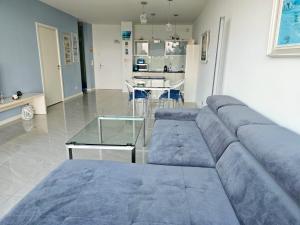 - un salon avec un canapé bleu et une table dans l'établissement BLUE MORNING - nowoczesny apartament z widokiem na morze PLAYA BALTIS, à Międzyzdroje