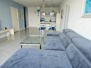 a living room with a blue couch and a table at BLUE MORNING - nowoczesny apartament z widokiem na morze PLAYA BALTIS in Międzyzdroje