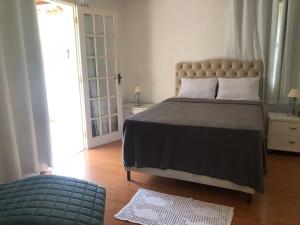 a bedroom with a large bed and a blue ottoman at Casa em Teresopolis in Teresópolis