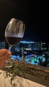 a person holding a glass of wine overlooking a city at Ampla, 180 graus de vista mar. in Ilhéus