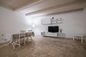 a white living room with a table and a television at MarGa's House in Bari