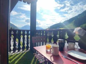 uma mesa com um copo de sumo de laranja numa varanda em Cozy studio between the lake and the mountain em Le Biot