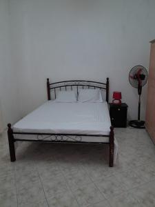 ein Schlafzimmer mit einem Bett mit weißem Bettlaken und einem Ventilator in der Unterkunft Le Serin Villa in Flic-en-Flac