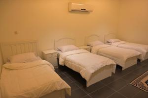 a group of four beds in a room at منتجع بيت الريف in Al Hofuf
