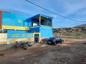 een blauw gebouw met een auto ervoor geparkeerd bij Boilers Surf House in Tamri