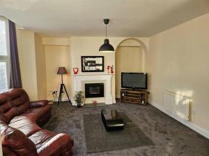 a living room with a leather couch and a television at Carlisle City Centre. Spacious Apartment. Ideal location. in Carlisle