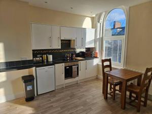 a kitchen with white cabinets and a table and chairs at Carlisle City Centre. Spacious Apartment. Ideal location. in Carlisle