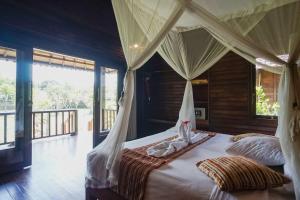 a bedroom with a canopy bed and a balcony at Abian Cottage Lembongan in Nusa Lembongan
