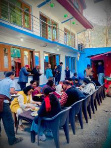 un grupo de personas sentadas en mesas comiendo comida en Al Hayat Guest House, en Pahalgām