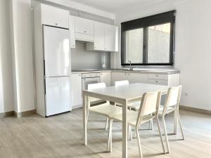 a white kitchen with a white table and chairs at Casa Antonio - apartamento Luna in Playa de San Juan