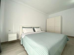 um quarto branco com uma cama grande e lençóis brancos em Casa Antonio - apartamento Luna em Playa de San Juan