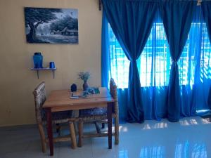 mesa de comedor con sillas y cortina azul en Spa Shallum, en Kibuye
