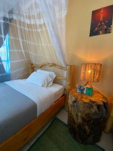 1 dormitorio con cama y mesa de madera con lámpara en Spa Shallum, en Kibuye