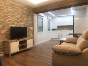 ein Wohnzimmer mit einem Sofa und einem TV in der Unterkunft Ventana a Santa María in Burgos