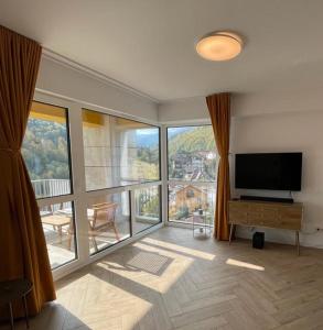 a living room with a flat screen tv and a large window at OHDA APARTMENT in Sinaia
