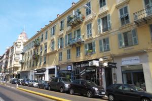 a street with cars parked in front of a building at Hotel Wilson in Nice