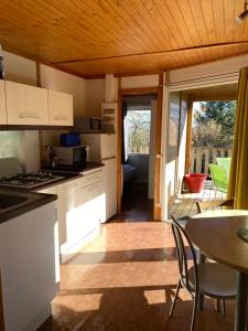 a kitchen with white appliances and a table with chairs at Charmant logement à la campagne, au calme in Manhac