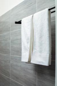 Duas toalhas brancas penduradas num toalheiro na casa de banho em BeHomu Apartments em Kira
