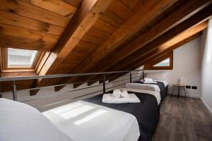 two beds in a room with wooden ceilings at La Casa del Sarto - Rooms and Apartments in Lecco