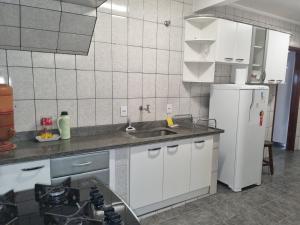 a kitchen with a sink and a refrigerator at Casa com dois quartos,dois banheiros,sendo uma suíte,sala de estar cozinha e garagem in Poços de Caldas